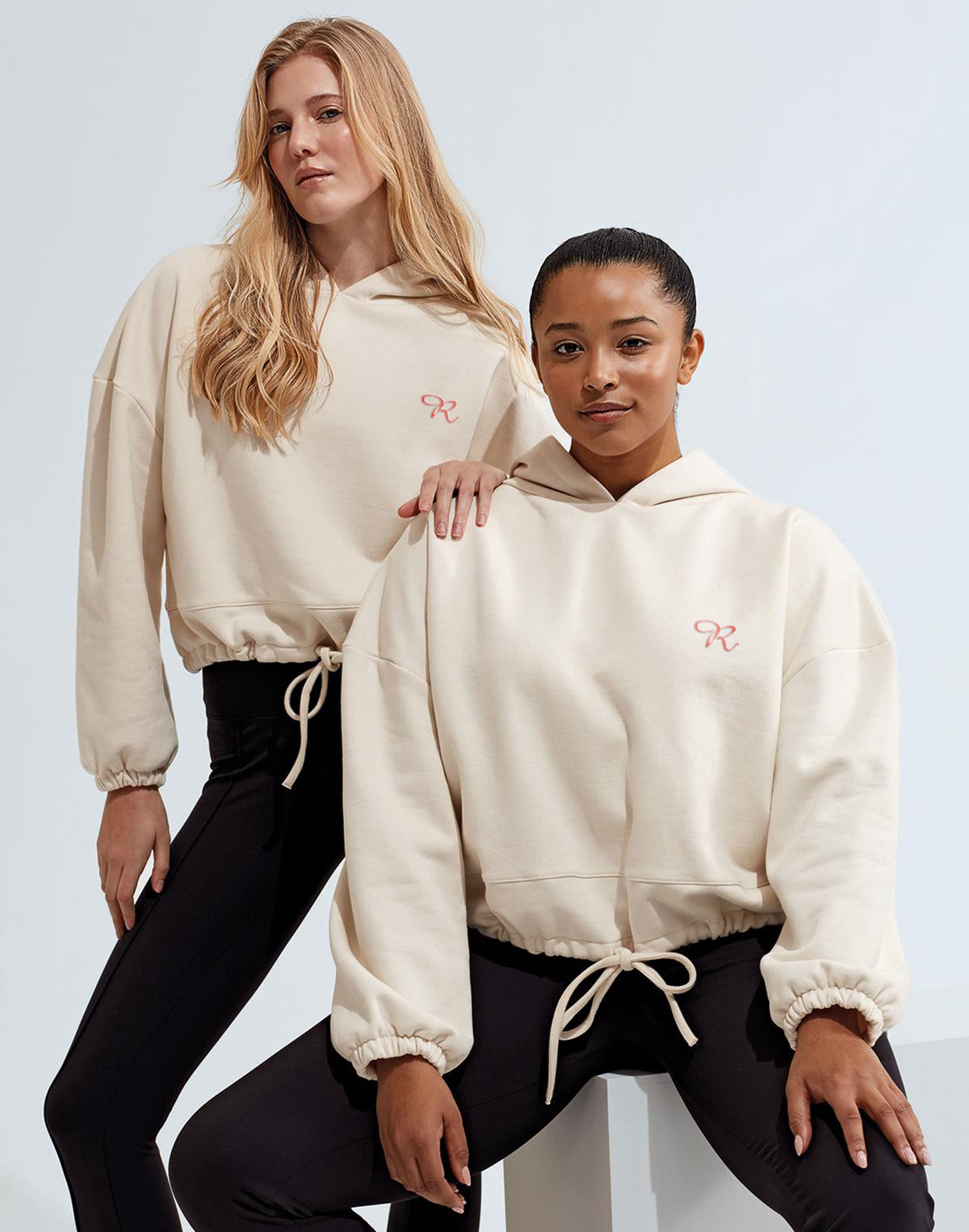 Two women confidently sporting Rival's oversized gym hoodies, exuding comfort and style. The hoodies feature Rival's signature logo prominently displayed, adding a touch of brand recognition to their athleisure look. The loose-fitting design and breathable fabric ensure freedom of movement during workouts, while the trendy oversized silhouette offers a fashionable edge. These hoodies are the perfect blend of functionality and fashion for active lifestyles